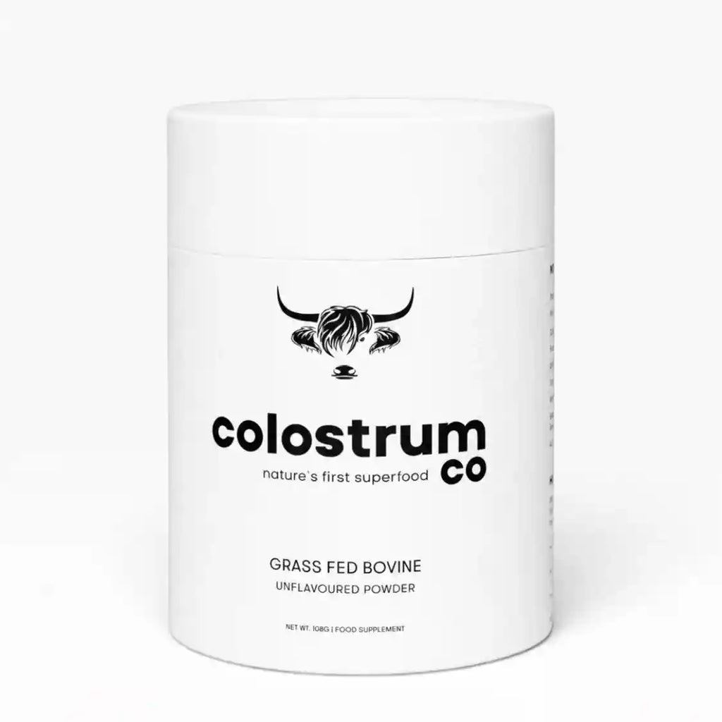 A white cylindrical plastic tub of Colostrum Co Grass Fed Bovine Unflavoured Powder, featuring a black bull logo and text on a clean white background.